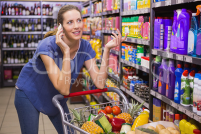 Pretty woman having a phone call and pushing trolley