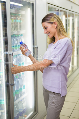 A pretty smiling blonde woman buying water