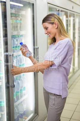 A pretty smiling blonde woman buying water A pretty smiling blonde woman buying water