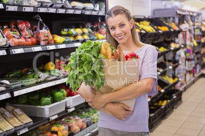 Pretty blonde holding bag with bread and vegetable