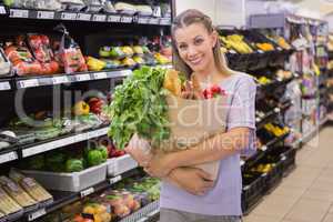 Pretty blonde holding bag with bread and vegetable