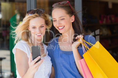 Happy smiling friends looking at smartphone