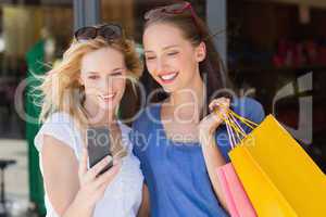 Happy smiling friends looking at smartphone