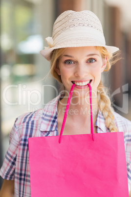 Blonde woman with shopping bag in her mouth