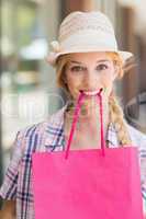 Blonde woman with shopping bag in her mouth