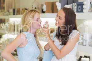 Smiling women spraying perfume