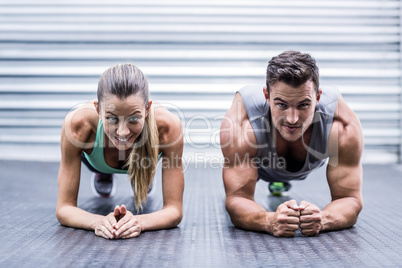 Muscular couple doing planking exercises