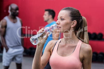 A muscular woman drinking a water