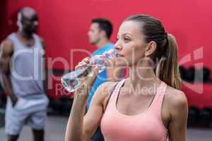 A muscular woman drinking a water