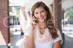 Portrait of smiling woman calling with smartphone and looking at