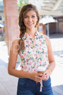 Portrait of smiling woman with coffee to go looking at camera