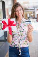 Portrait of smiling woman showing gift box and credit card to th