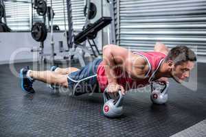 Muscular man doing push-ups with kettlebells