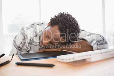 Exhausted casual businessman sleeping on desk