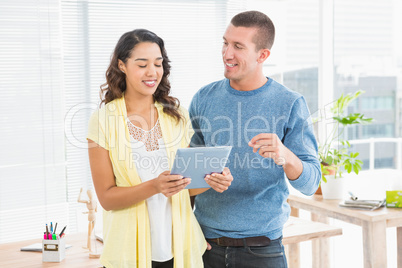 Smiling colleagues working together with tablet computer