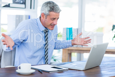 Confused businessman looking at laptop computer