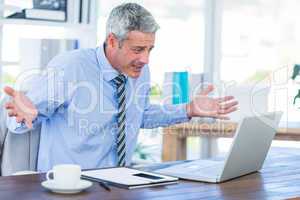 Confused businessman looking at laptop computer