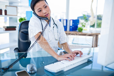 Doctor having phone call and using her computer