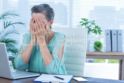 Anxious businesswoman with head in hands