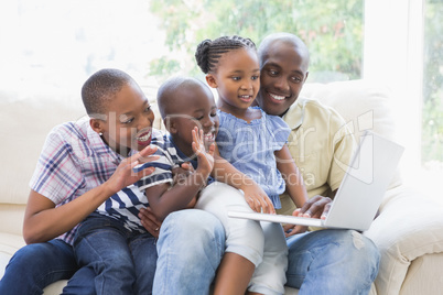 Happy family on the couch chatting with laptop