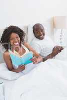 Portrait of a happy smiling couple reading in bed together