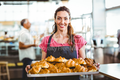 Baker showing tray of fresh croissant