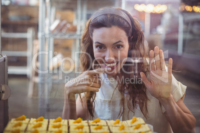 Pretty brunette looking at camera through the glass with finger