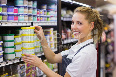 Portrait of a smiling blonde worker taking a products