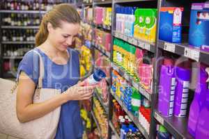 Thoughtful pretty brunette looking at product in shelf