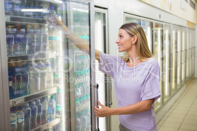 A pretty smiling blonde woman buying water