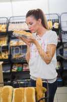 A woman smelling bread in the pastries shelf