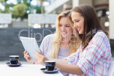 Happy women friends looking at tablet