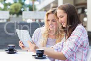 Happy women friends looking at tablet