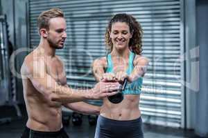A muscular trainer show how to lift kettlebells