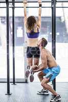 A trainer lifting a muscular woman