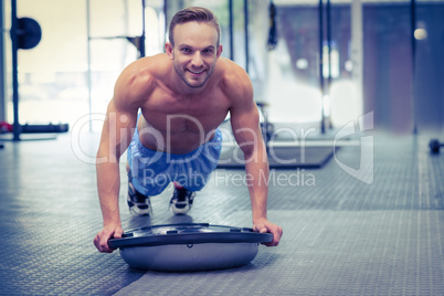 Muscular man doing bosu ball exercises