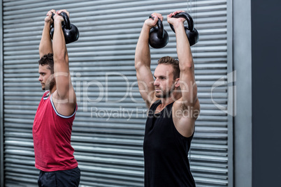 Muscular men lifting a kettle bell