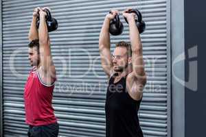 Muscular men lifting a kettle bell