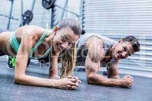 Muscular couple doing planking exercises