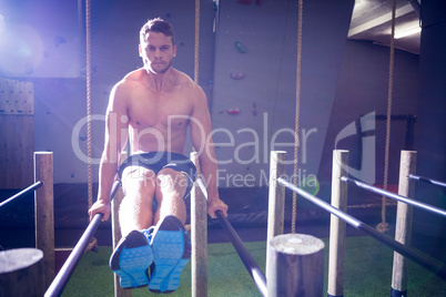 Muscular man exercising on parallel bars