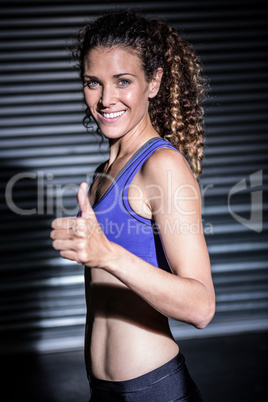 Portrait of smiling muscular woman looking at camera with thumb