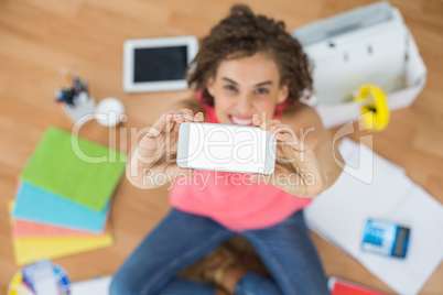 Young creative businesswoman showing her phone
