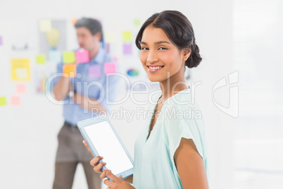 Creative businesswoman using tablet with colleague behind her