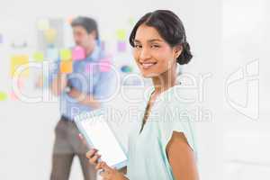 Creative businesswoman using tablet with colleague behind her