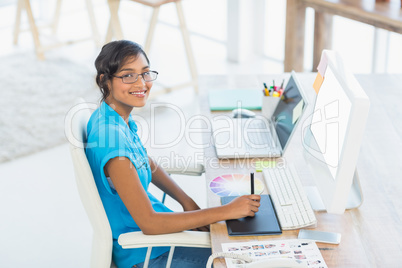 Smiling casual businesswoman working on digitizer and holding c