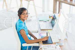 Smiling casual businesswoman working on digitizer and holding c