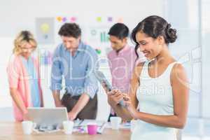 Casual businesswoman using digital tablet with colleagues behind
