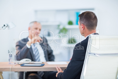 Two businessmen sitting and speaking