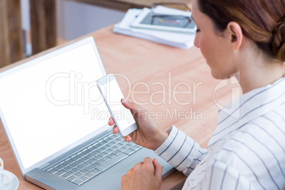 Brunette businesswoman smiling using laptop and her mobile