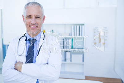 Happy male doctor looking at camera with arms crossed